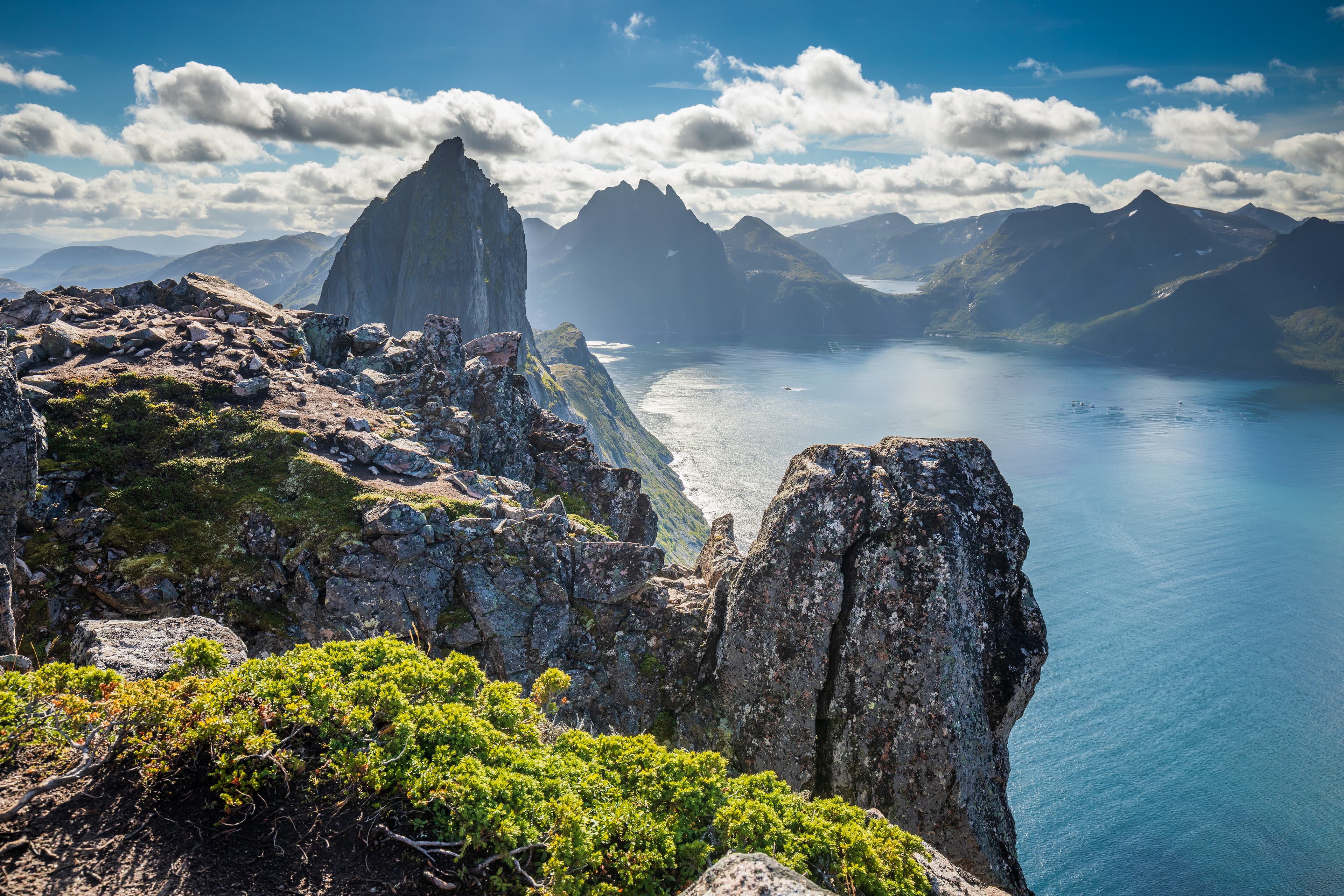 Simo Räsänen · CC BY-SA 4.0 The coastal cliffside of Hesten in Senja, Troms og Finnmark, Norway in 2022 August. The near by mountain on the center left is Segla. The further mountain in the center is Breidtinden. The fjord below is Mefjorden. Svartholvatnet lake can be seen far ahead on the center right.