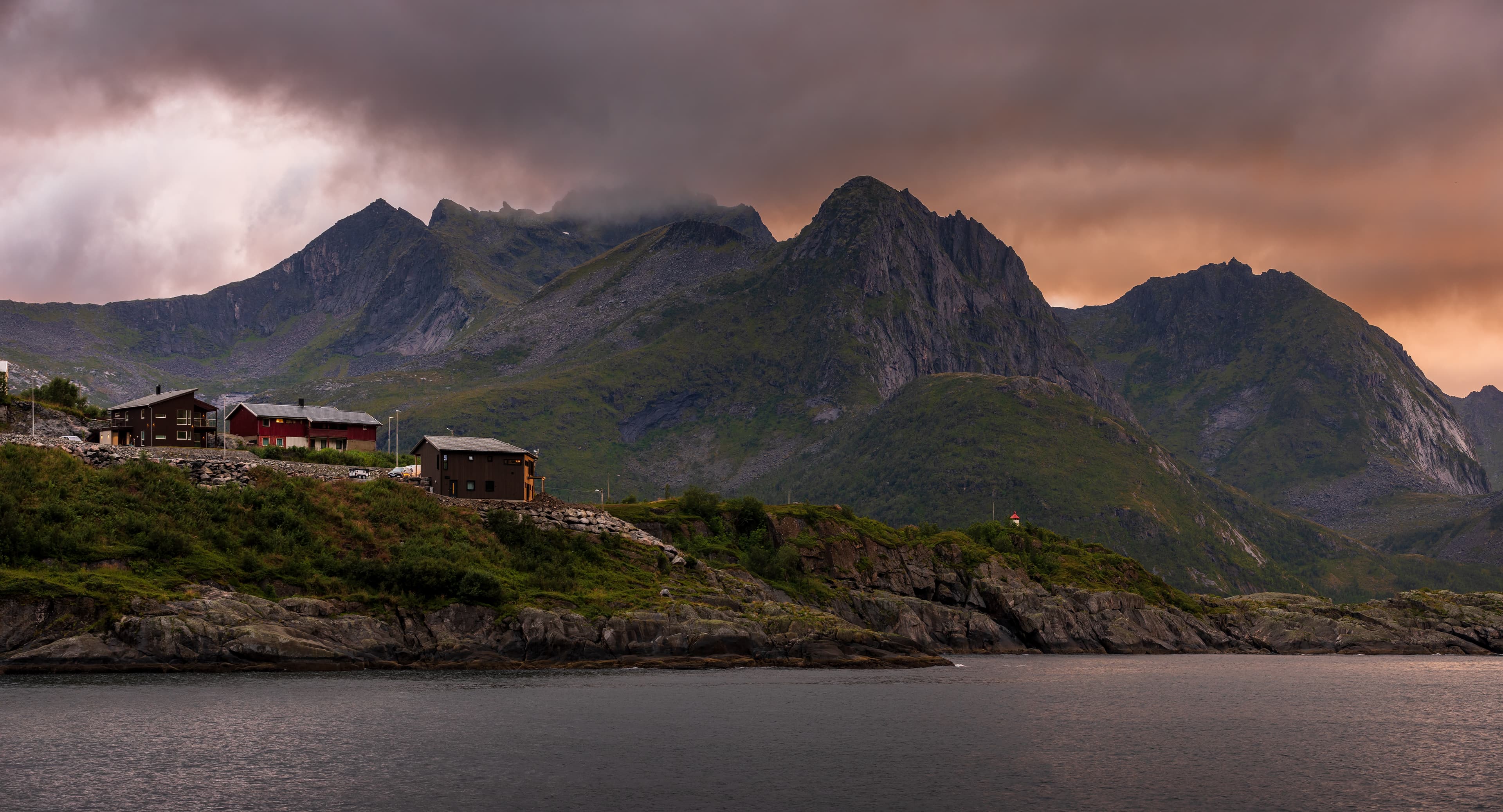 Simo Räsänen · CC BY-SA 4.0 Skultran mountain range behind Husøy village in evening in Senja, Troms og Finnmark, Norway in 2022 August. The mountains are observed over Husøysundet of Øyfjorden.